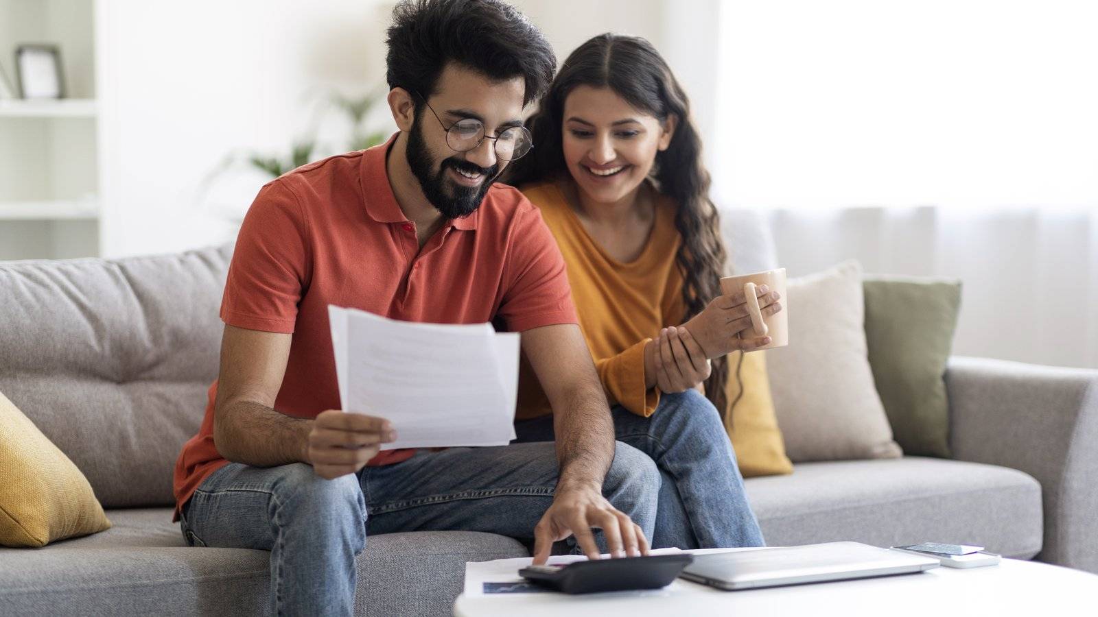 Young couple on a sofa reading a letter and using a calculator